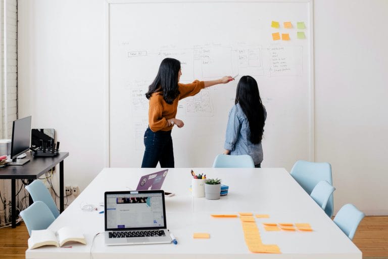 Two people working through an idea on a whiteboard