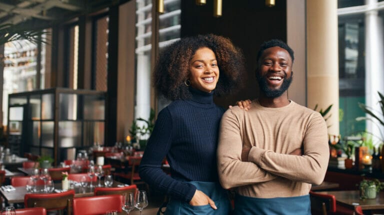 Two people smiling in a restaurant with red chairs
