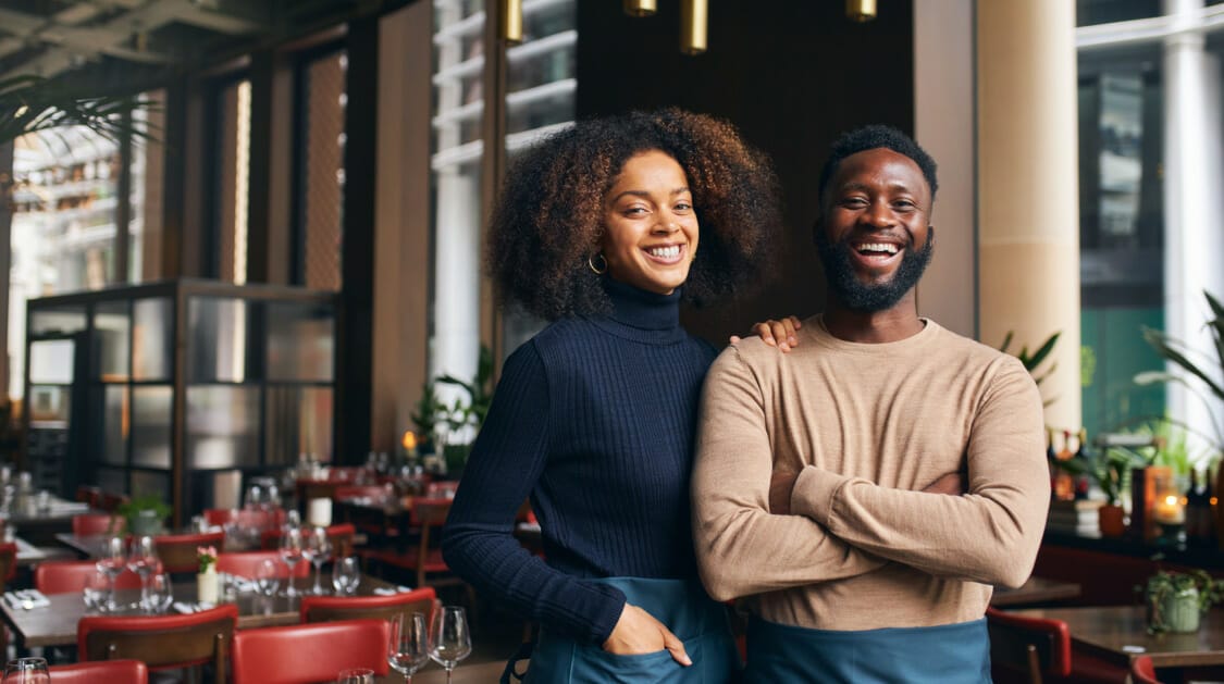 Two people smiling in a restaurant with red chairs