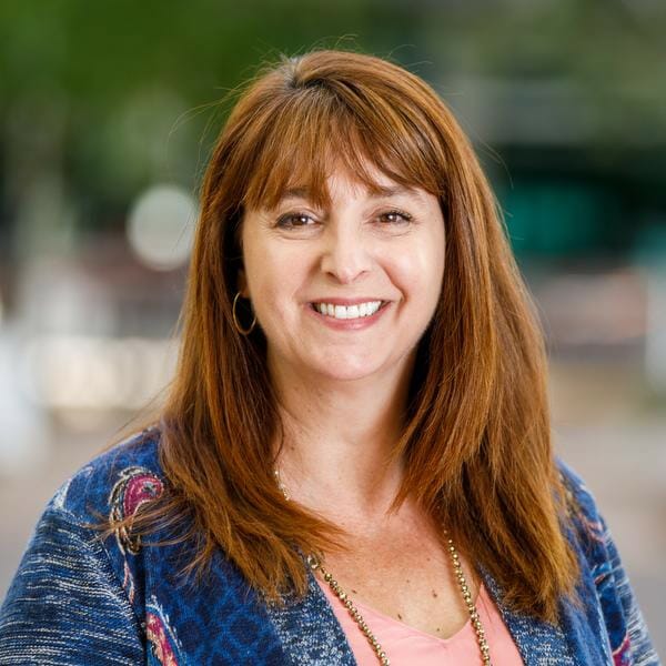Woman smiling in blue top with green background