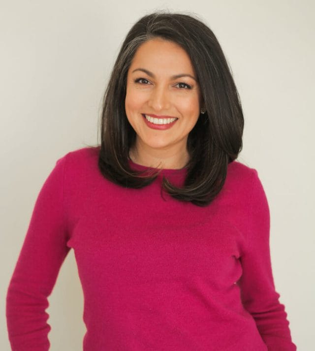  A smiling woman with dark hair and a long sleeve top