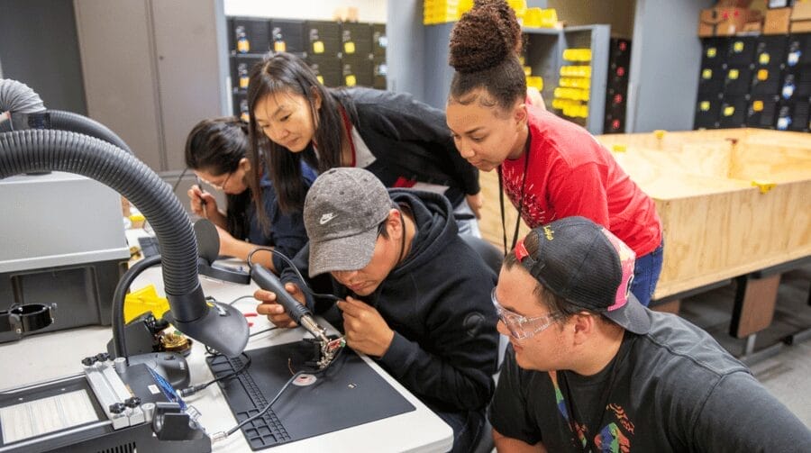 Five people working together with machinery on a table