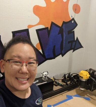 A person wearing glasses and smiling in a makers space