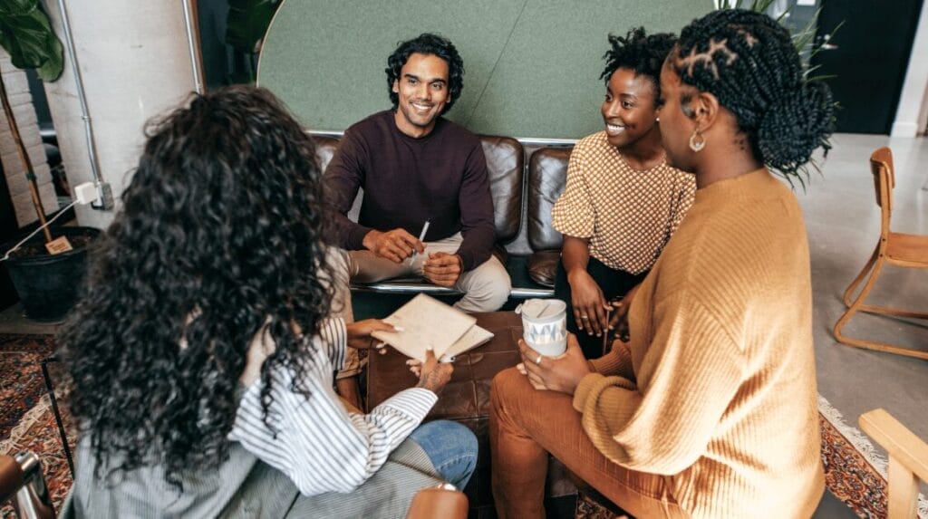 Four people sitting and smiling inside a casual office space