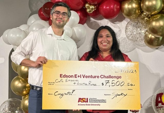 Two people standing next to each other smiling and holding a large check for the Edson E+I Venture Challenge