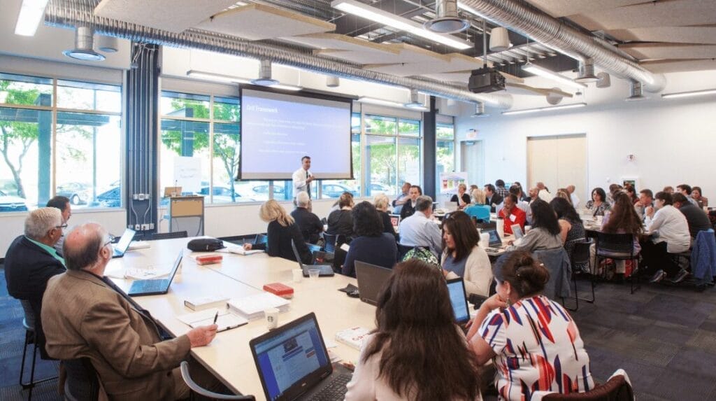 A large group of people watching a speaker at a networking event for business owners
