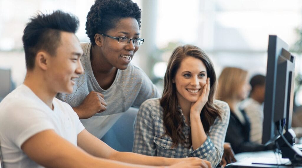Three students working at a computer station
