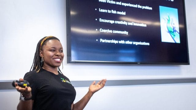 A person smiling while she presents her business on a large flat screen