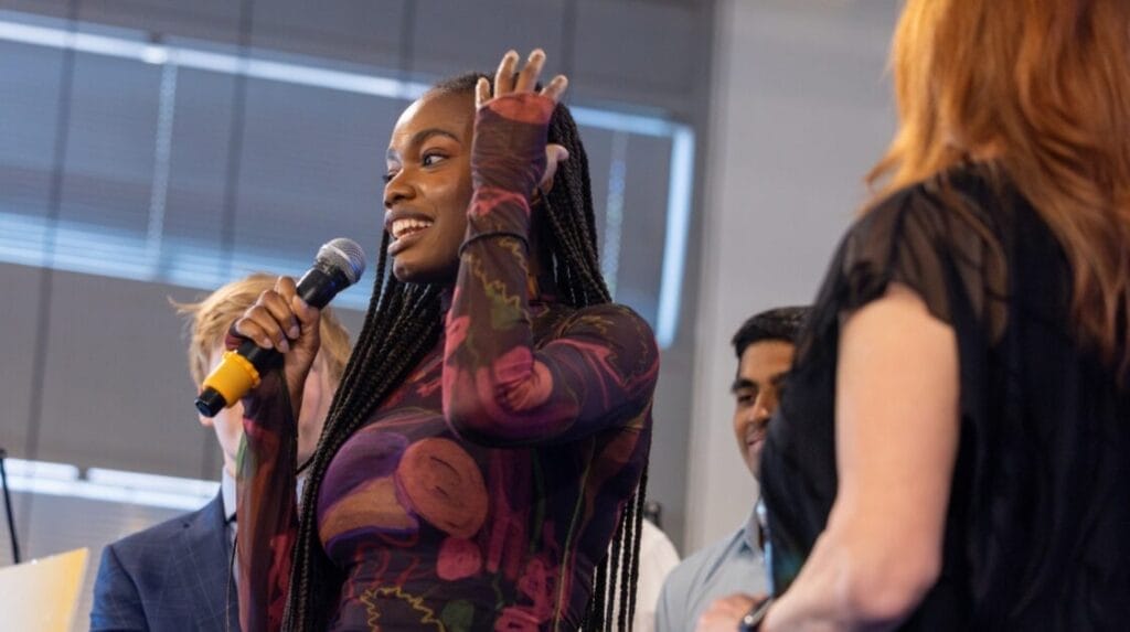 A person smiling and holding a microphone at Demo Day, a startup pitch competition 