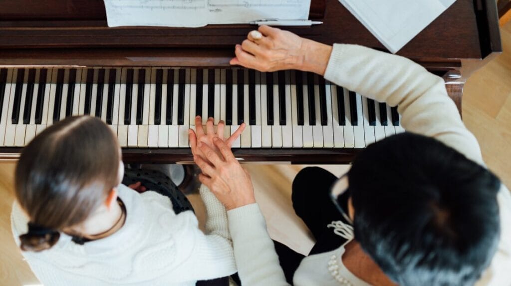 A music teacher teaching a child a piano lesson