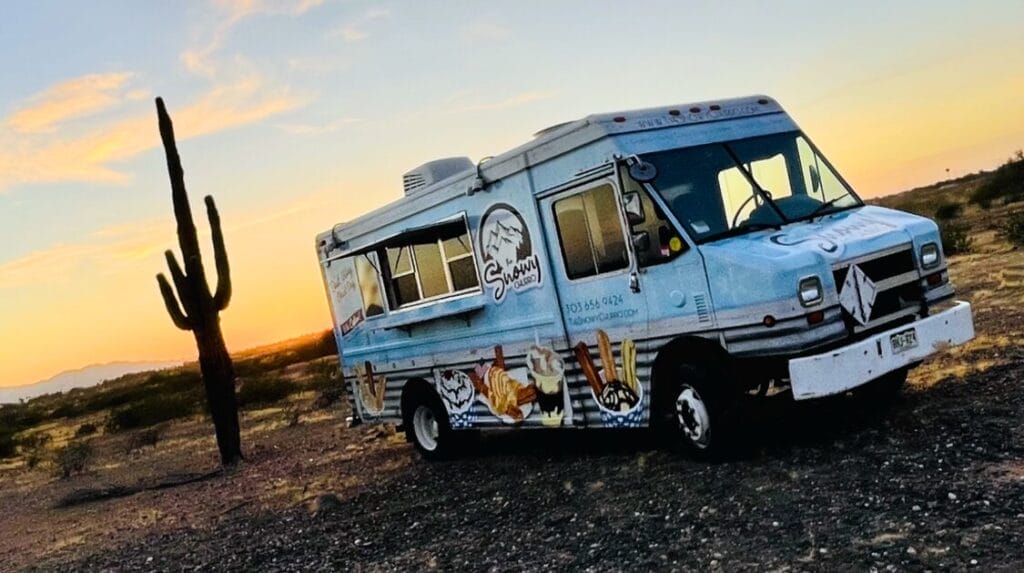 A food truck parked in the desert at sunset