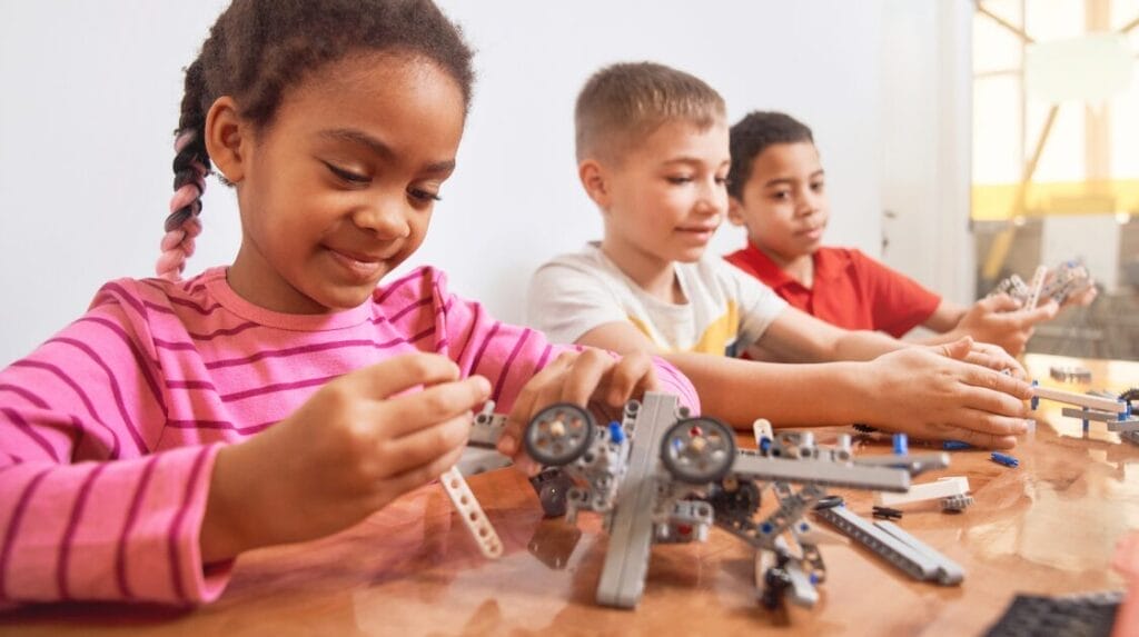 Group of three kids sitting at a table building a project