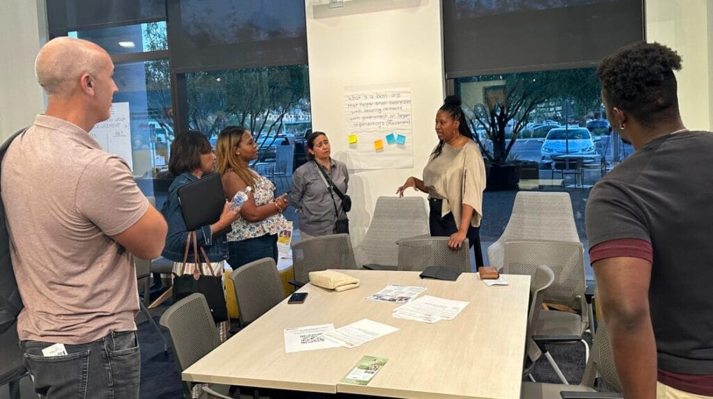 People standing around a conference table talking about entrepreneurship ideas