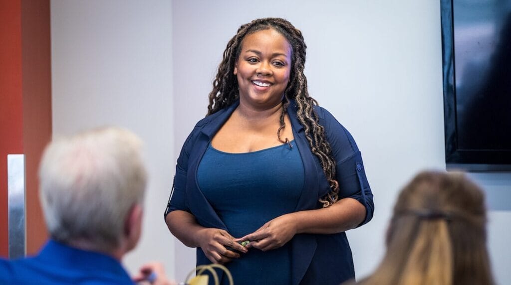 A person smiling at an audience at a professional event