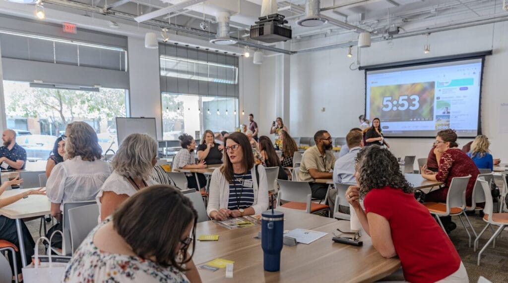 People sitting at tables at a professional event having conversations
