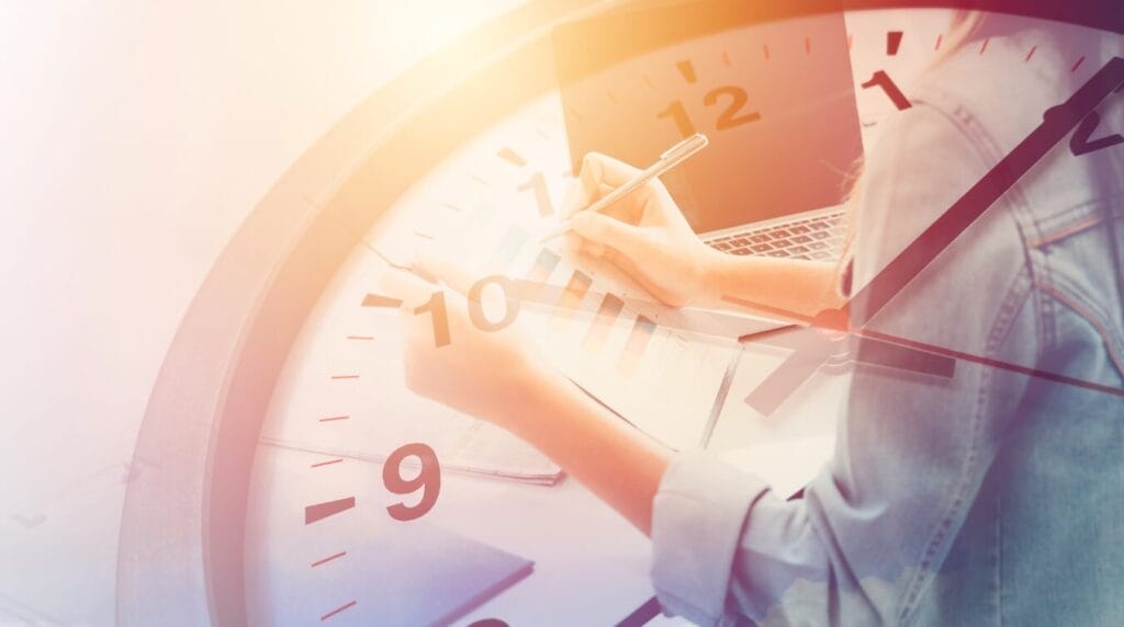 View from above of person writing over an image of a clock