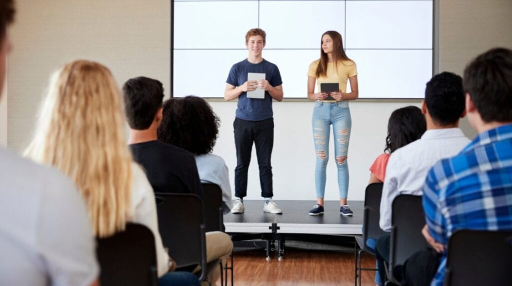 High school students standing on a short stage sharing their ideas with an audience