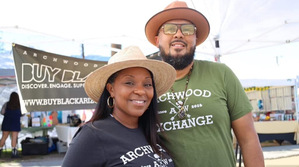 Two people wearing hats and smiling at an outdoor market