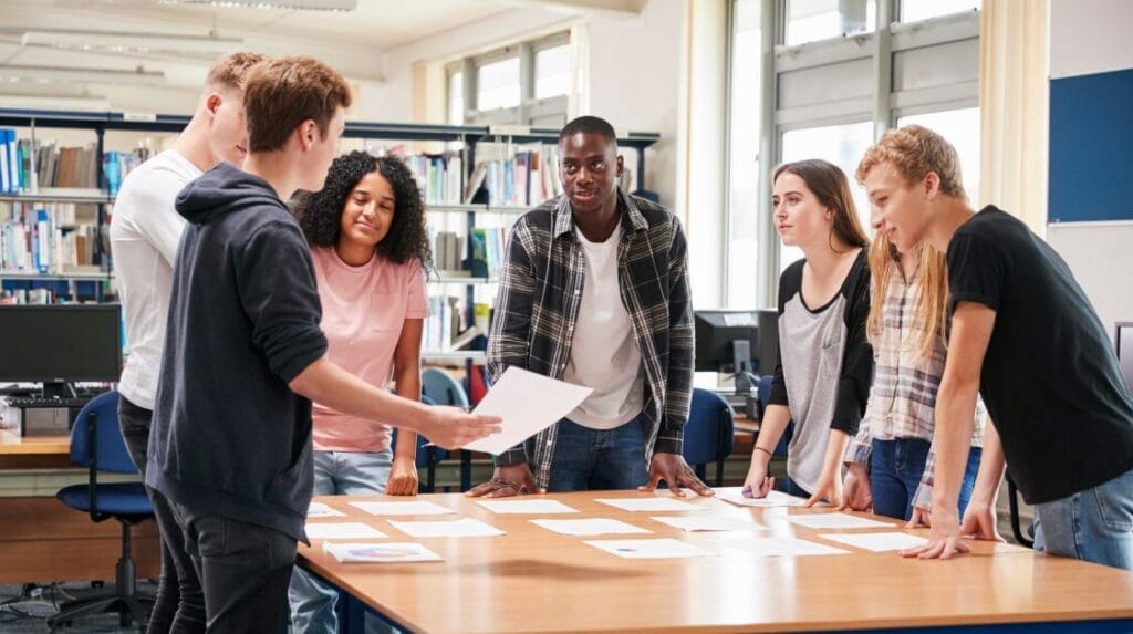 Seven college students standing at a table and collaborating on ideas