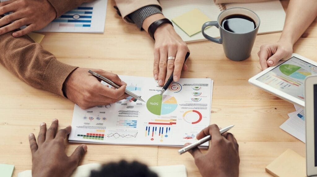 A view from above looking down at a table with business data on a sheet with people looking at it