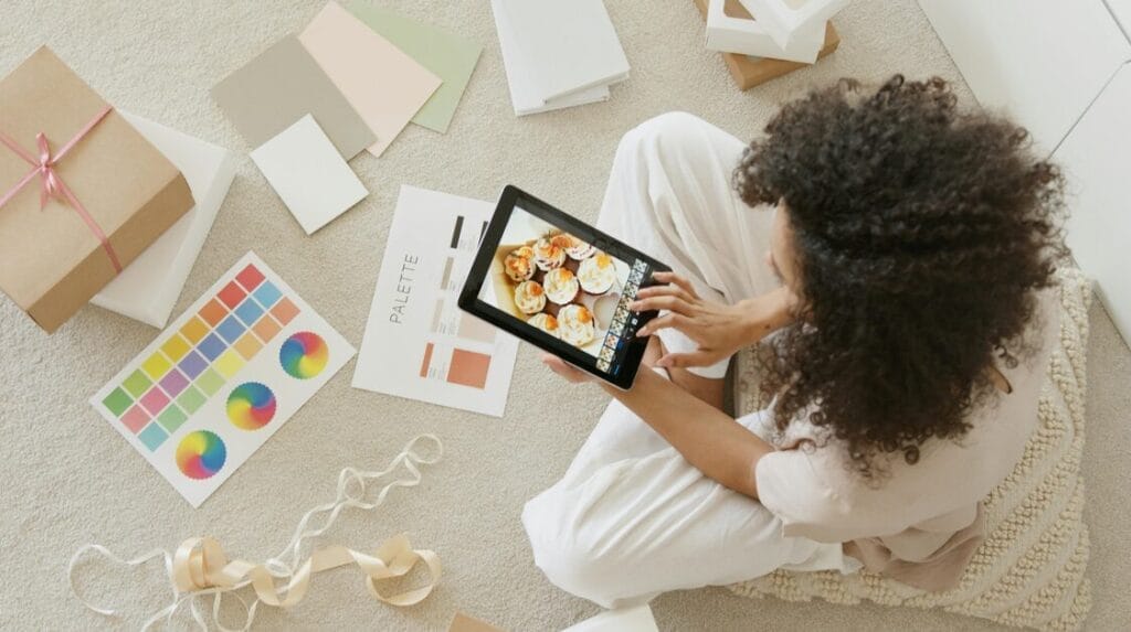 A person sitting on the floor looking at a computer tablet surrounded by shipping materials