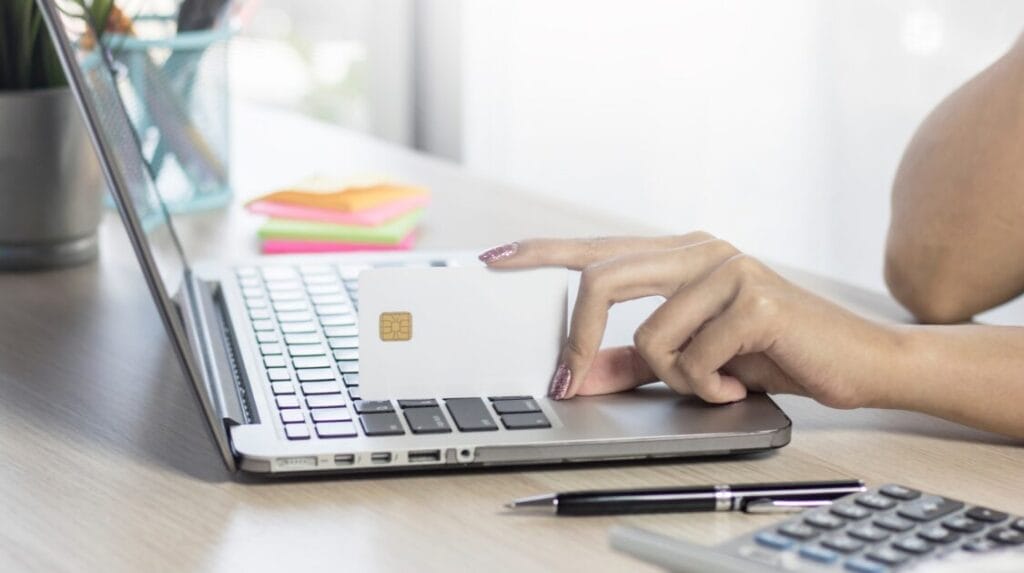 A person using a laptop and holding a credit card