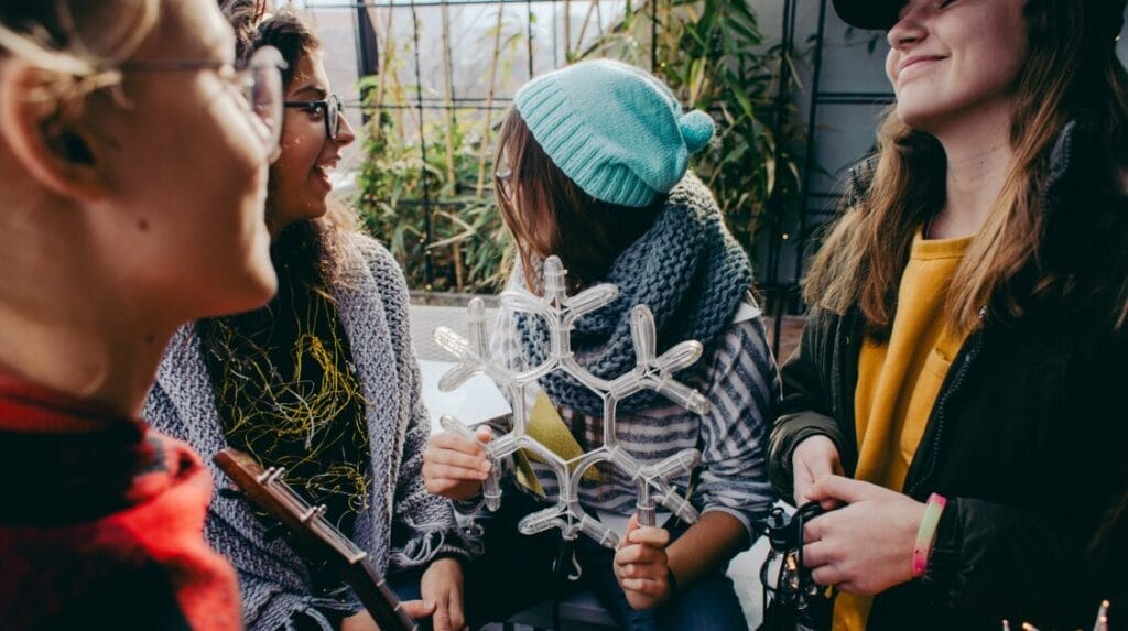 Four teenagers outside wearing fall clothing and holding a snowflake