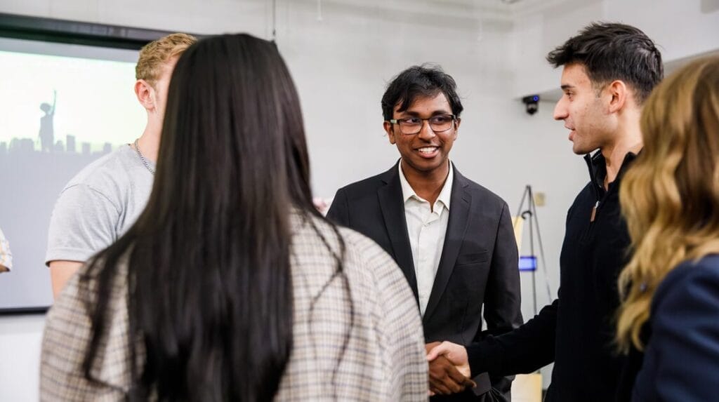 Alt text: Five people at an entrepreneurial event and two shaking hands