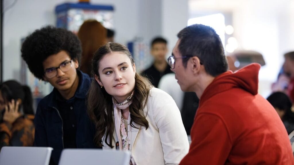 Three people sitting in the audience and talking at the Venture Devils Demo Day event