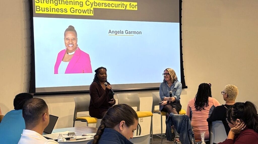Two people sitting and speaking in front of an audience at a professional event