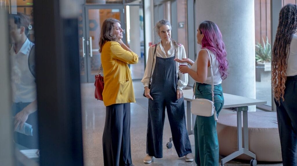 Three people standing and talking at a professional event