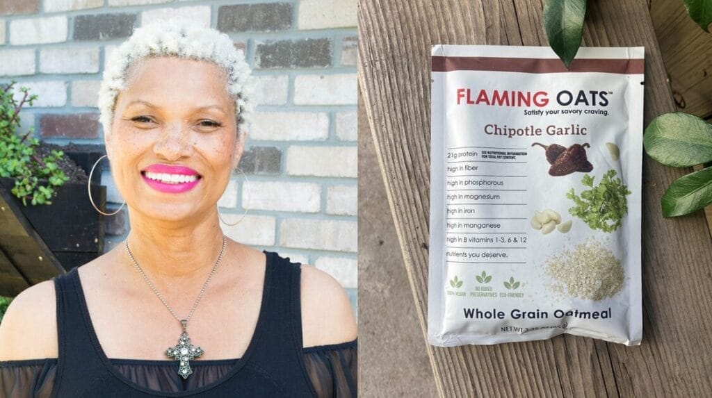 A person smiling at the camera, wearing a cross on a necklace with a brick wall in the background and a package of Flaming Oats on the other side of the photo