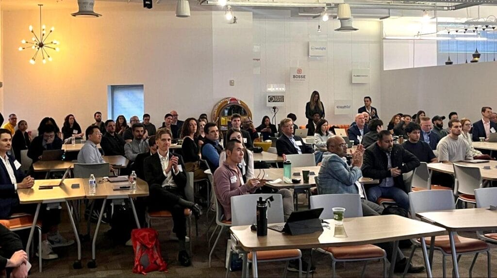 A large group of people sitting at tables at an entrepreneurial pitch event.