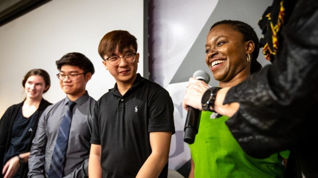 Five people on stage at a Venture Devils Demo Day event with one person smiling and speaking into a microphone.