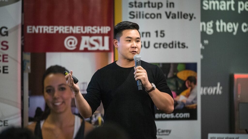 A startup founder holding a microphone and presenting at an ASU pitch event