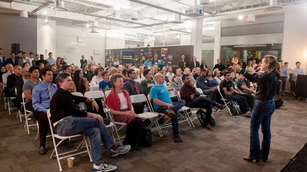 A person standing in front of a seated audience at a startup event.