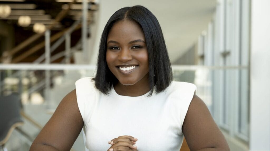 A person sitting, smiling, and looking directly at the camera.