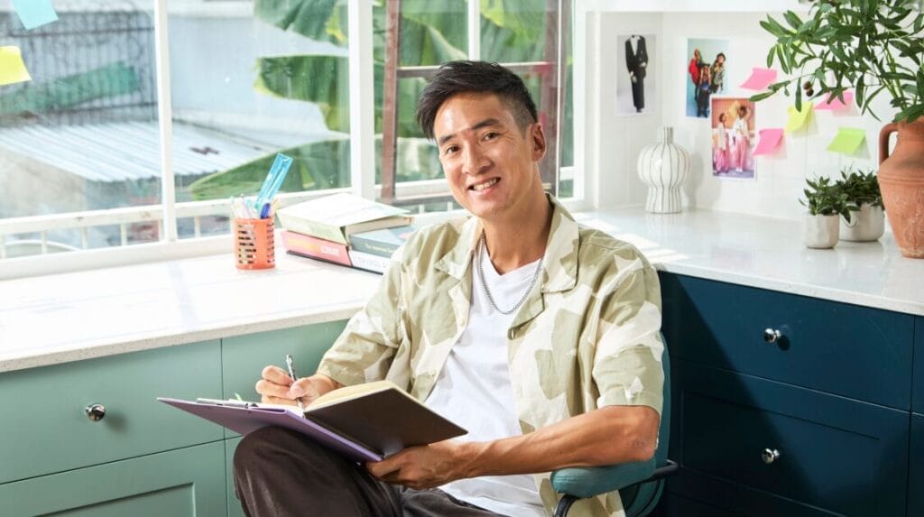A person sitting in a home office holding a notebook and a pen