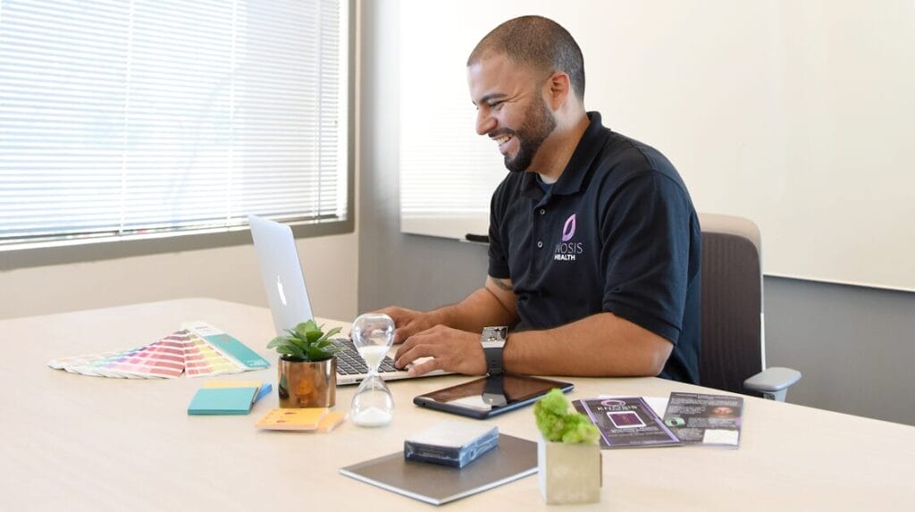 A person sitting at a table and typing on his laptop.