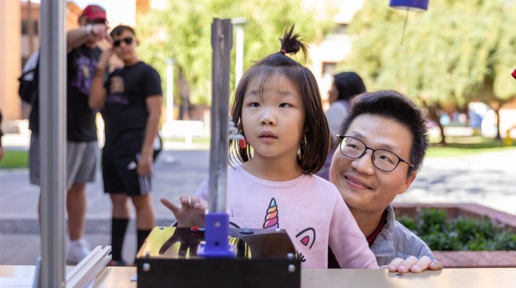 A parent and child interact with a STEM  display at an ASU Open Door event 