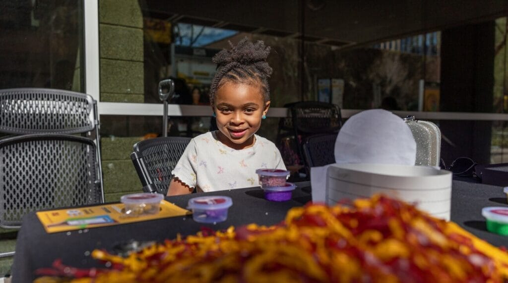 A child sitting outdoors at a table playing with crafts.