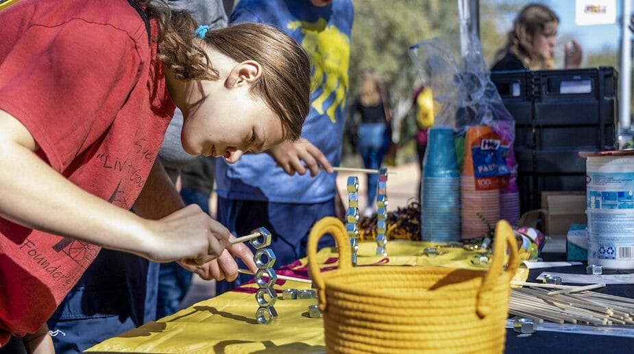 A teenager experimenting with a variety of materials at a table.