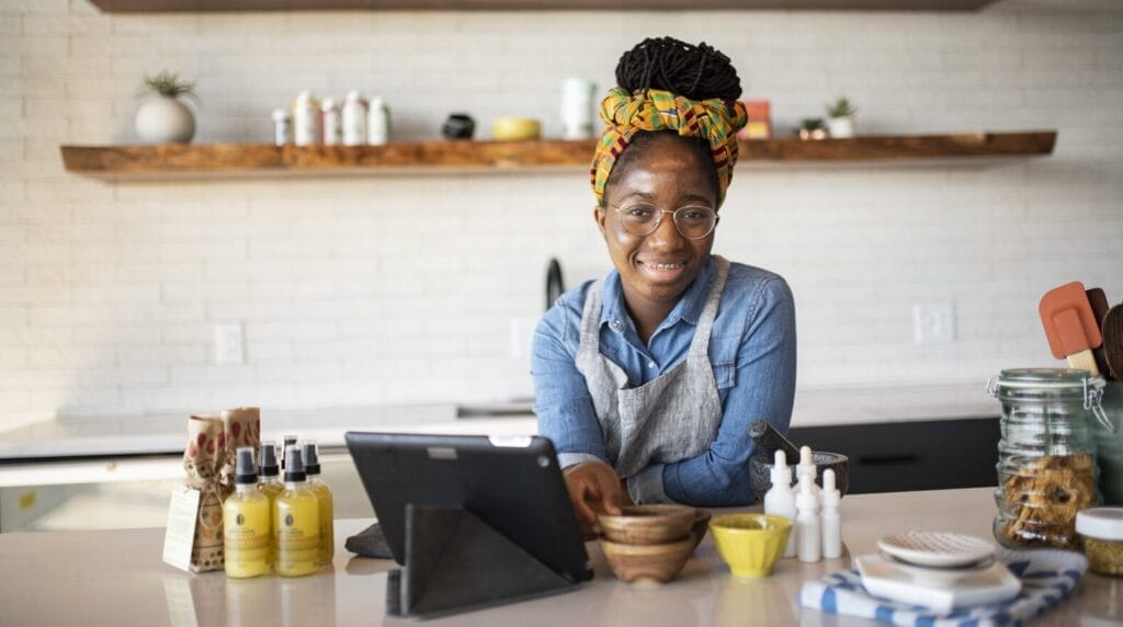 A person standing at a counter with their products and a POS system on the counter.