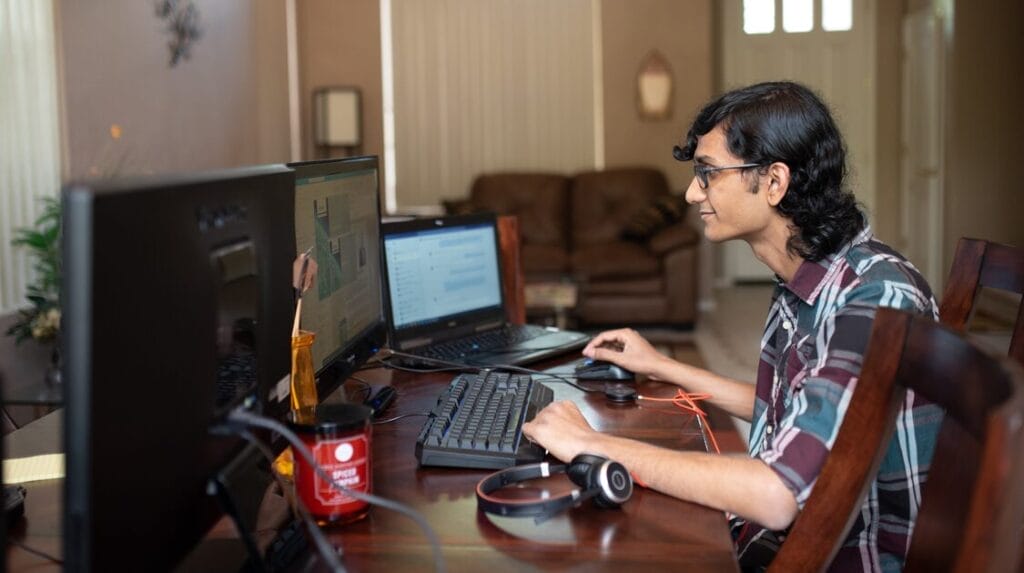 A person sitting at a desk at home and smiling at a computer screen.