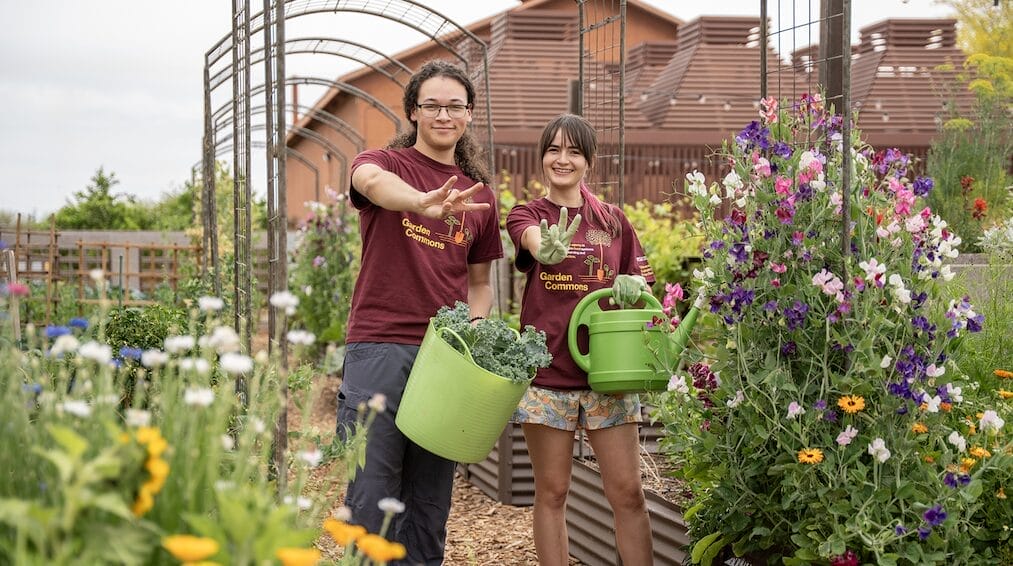  Two students working together in a campus garden, engaging in hands-on outdoor activities.