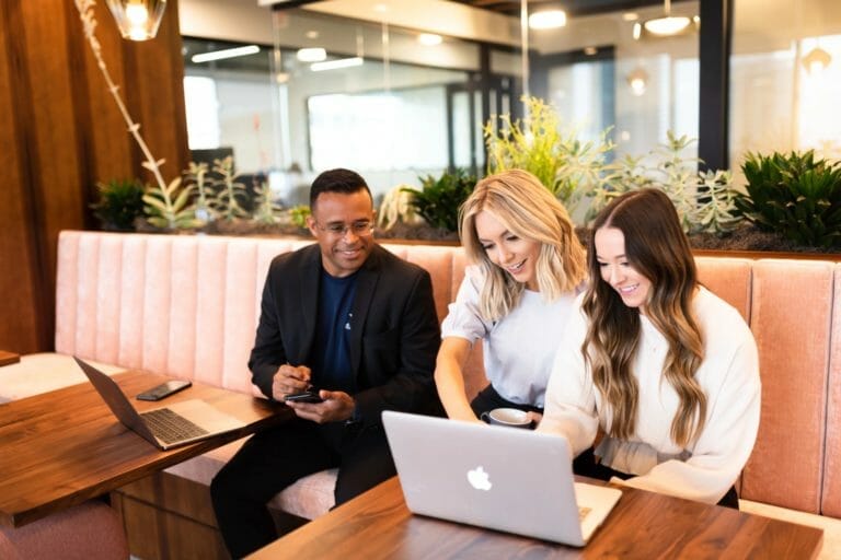 Two women, one man, looking at a laptop