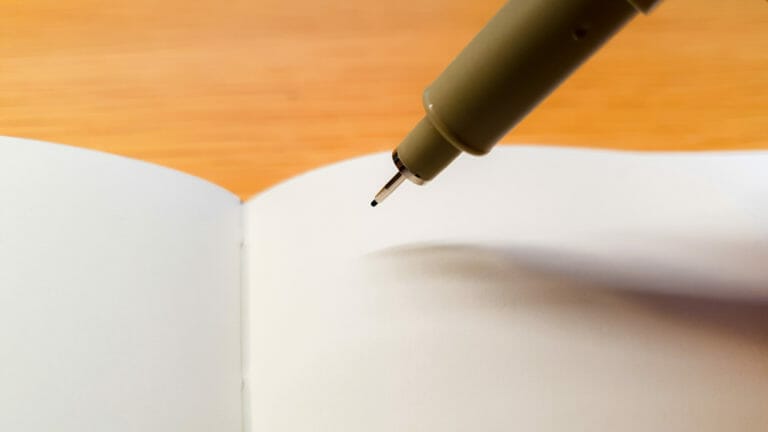 Pen hovering over a blank piece of paper