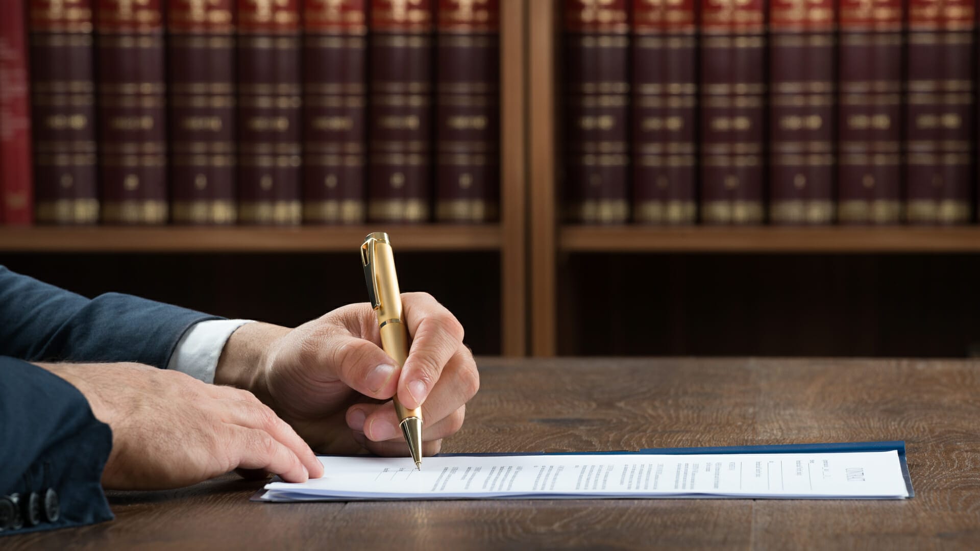 Cropped image of male lawyer writing on legal documents at desk in courtroom