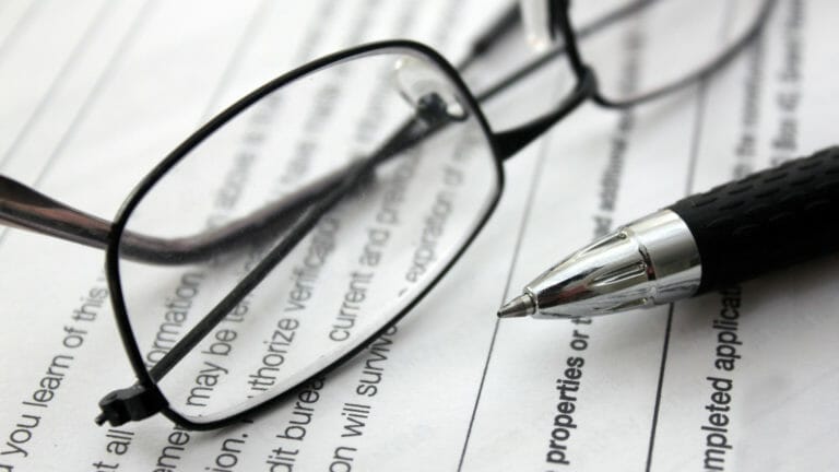 Glasses and a pen sitting on a table on top of a piece of paper