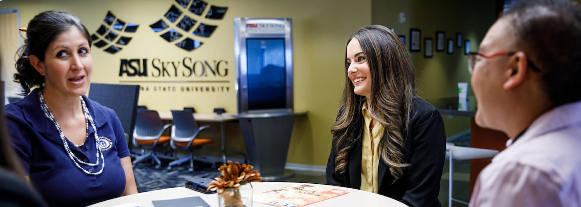 Three people sitting at conference table.